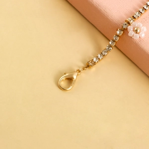 Detail view of gold rhinestone anklet featuring a pink bead daisy flower charm and lobster clasp