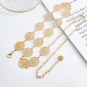 Macro detail of golden multi-layer metal waist chain with hollow flower patterns and rose pendant