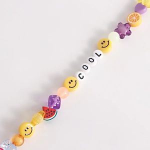 Close-up of handmade beaded shoe charm with fruit slices and COOL letter beads
