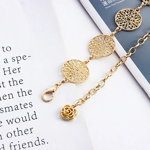 Detailed view of a gold metal waist chain with hollow circular patterns and rose pendant