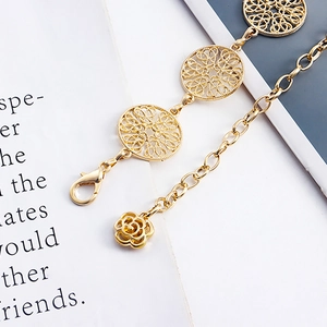 Detail of gold metal waist chain with hollow round discs and a delicate rose pendant