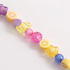Detailed close-up of handmade beaded shoe chain with colorful resin fruit and smiley faces