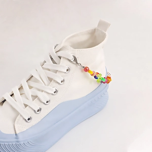 Colorful beaded shoe charm with mixed fruits and smiley face on white canvas sneakers