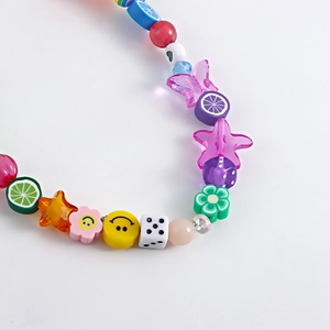 Detailed macro view of Y2K style colorful fruit and smiley face beads on shoes charm chain