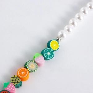 Macro shot of colorful polymer clay fruit beads and white pearls for jewelry accessory