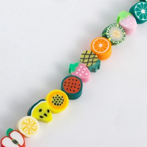 Close-up of mixed polymer clay fruit beads including strawberry and lemon for DIY jewelry
