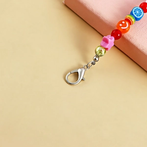 Close-up of colorful fruit charm chain with stars and lemon beads on warm beige backdrop