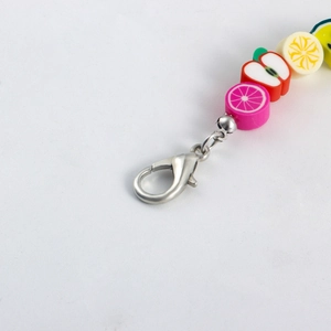 Macro view of colorful fruit beads and metal lobster clasp on a creative shoe chain