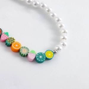 Detail shot of colorful polymer clay fruit beads and white pearls for shoes or anklets