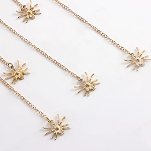 Detail of five golden spider charms with thin metal chains for beach leg jewelry