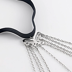Detail eines schwarzen Chokers mit silbernem Schmetterlingsanhänger und Metallquasten