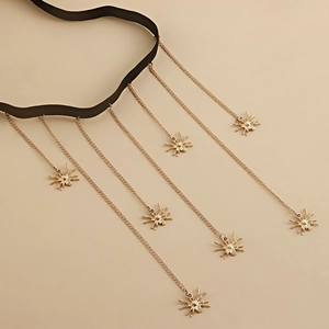 Gothic choker with golden chains and seven spider pendants on a beige background