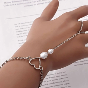 Detail eines silbernen Herz-Fingerarmbands mit Perlen und Punk-Metallkettengliedern