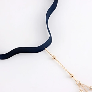 Detail of black elastic leg ring featuring gold metal chains and dangling bead charms