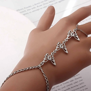 Detail eines silbernen Schmetterlings-Fingerarmbands mit Hohl-Design auf Buchhintergrund