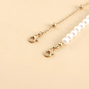 Detailed macro view of gold lobster clasps with white imitation pearl beads and chain