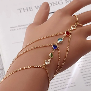 Detail eines mehrlagigen goldenen Fingerarmbands mit fünf farbigen Edelsteinen im Boho-Stil