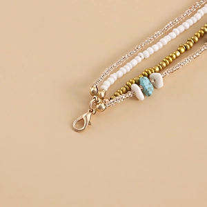 Detail of bohemian layered beads with turquoise stone and golden lobster clasp