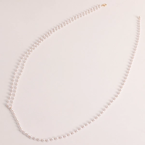 Detail of double-layer faux pearl waist chain with elegant gold metal lobster clasp