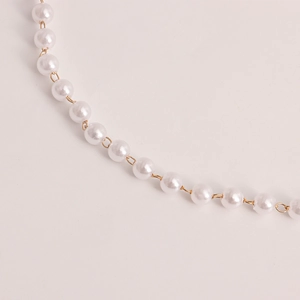 Close-up of elegant double-layered faux pearl waist chain with golden metal connector rings