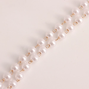 Detail of double-layer waist chain featuring white pearls and gold metal rings links