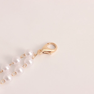 Detailed close-up of double-layer faux pearl waist chain with gold lobster clasp