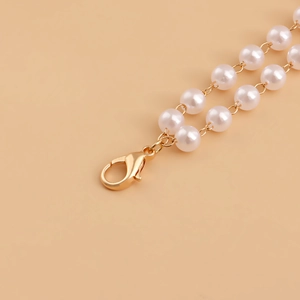 Macro shot of double-layer faux pearl waist chain with golden lobster clasp detail