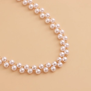 Detail shot of the elegant double-layer faux pearl waist chain with gold metal links