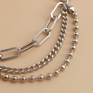 Detail of multi-layered silver chain featuring cuban links, bead chain and long link textures