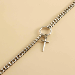 Close-up of a polished silver Cuban link chain with a dagger pendant and round clasp