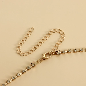 Dettaglio della catena da gamba in strass dorati con chiusura a moschettone e maglie