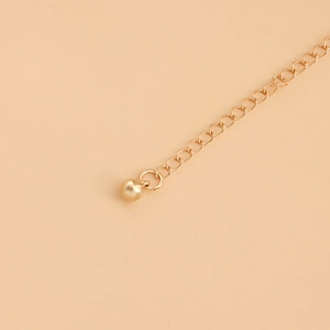 Détail macro de la chaîne de taille dorée avec un pendentif boule en métal poli