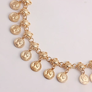 Gros plan sur une chaîne de taille dorée ornée de pendentifs de monnaie Elizabeth II