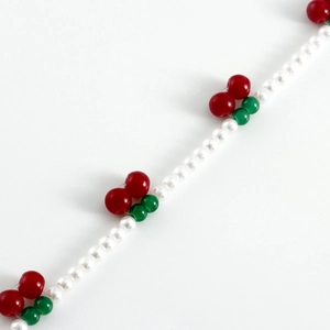 Détail de la chaîne de taille avec perles blanches et accents de cerise rouge
