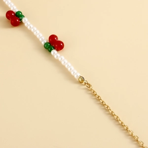 Détail de la chaîne de taille en perles avec cerises rouges et finition métal doré