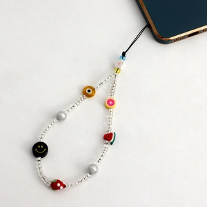 Détail du bijou de téléphone bohème avec perles colorées, fruits et œil porte-bonheur