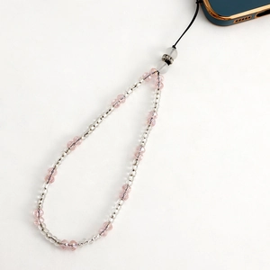 Close-up of pink and transparent faceted crystal beads on a phone charm strap with metal spacers