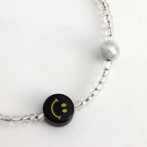Vue détaillée du cordon de téléphone bohème avec perles argentées et breloque smiley jaune