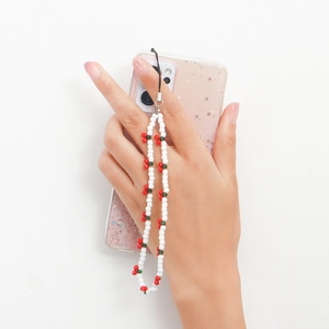 White beaded phone lanyard with cute red cherry charm design in a handheld display