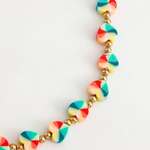 Detail of colorful rainbow heart beads and gold metal spacers on a handmade strap