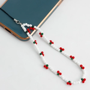 Close-up of white beaded phone lanyard with red cherry charm on a smartphone case