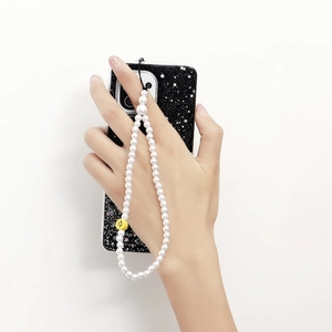 Dragonne de téléphone en perles blanches avec breloque smiley jaune tenue en main