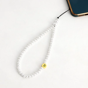 Détail de la lanière de téléphone avec perles blanches et perle smiley jaune décorative