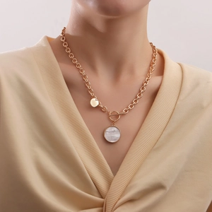Dettaglio ravvicinato di una collana dorata in madreperla con chiusura a T e catena spessa