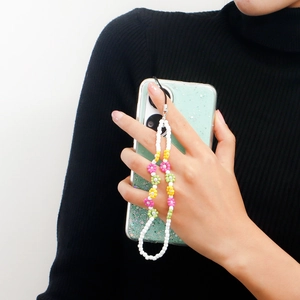 Detail of handmade beaded phone strap with colorful floral charms on glitter phone case