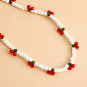 Close-up of handmade white beads phone lanyard with red cherry charm accents