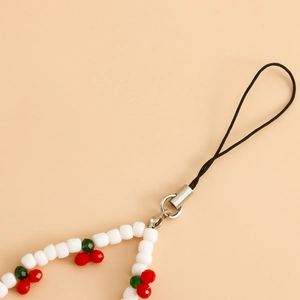 Detail of white beaded phone strap featuring red cherry accents and silver metal clasp