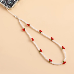Detail shot of white seed bead phone strap featuring decorative red cherry charms
