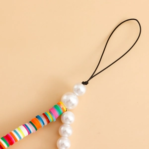 Vue détaillée de perles Heishi colorées et de fausses perles blanches sur un cordon fait main