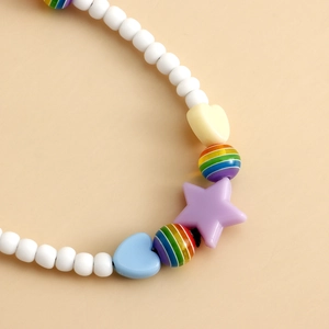Gros plan de perles blanches avec étoile violette et breloque cœur arc-en-ciel